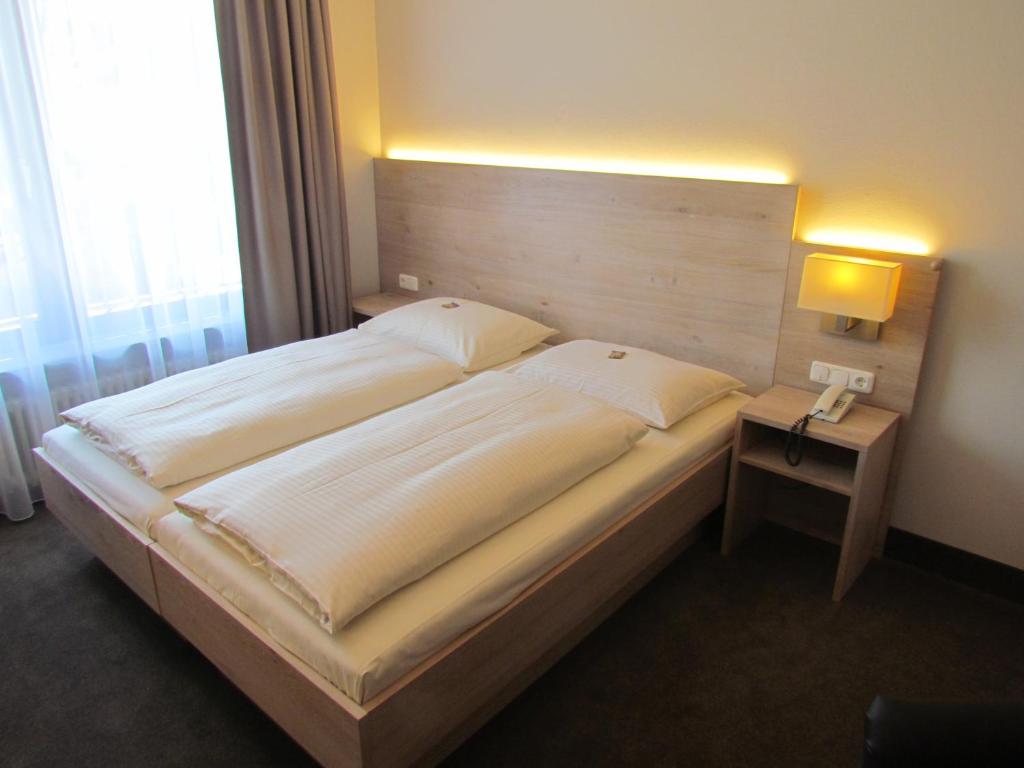慕尼黑卢特尔酒店的一间卧室配有一张大床和木制床头板