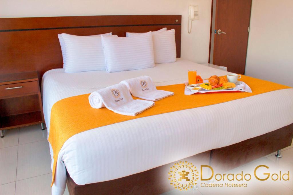波哥大Hotel Dorado Gold的一张带两条毛巾的床和一盘食物