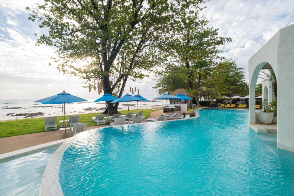 蔻立拷叻海洋微风度假酒店的一个带遮阳伞和椅子的游泳池以及海滩
