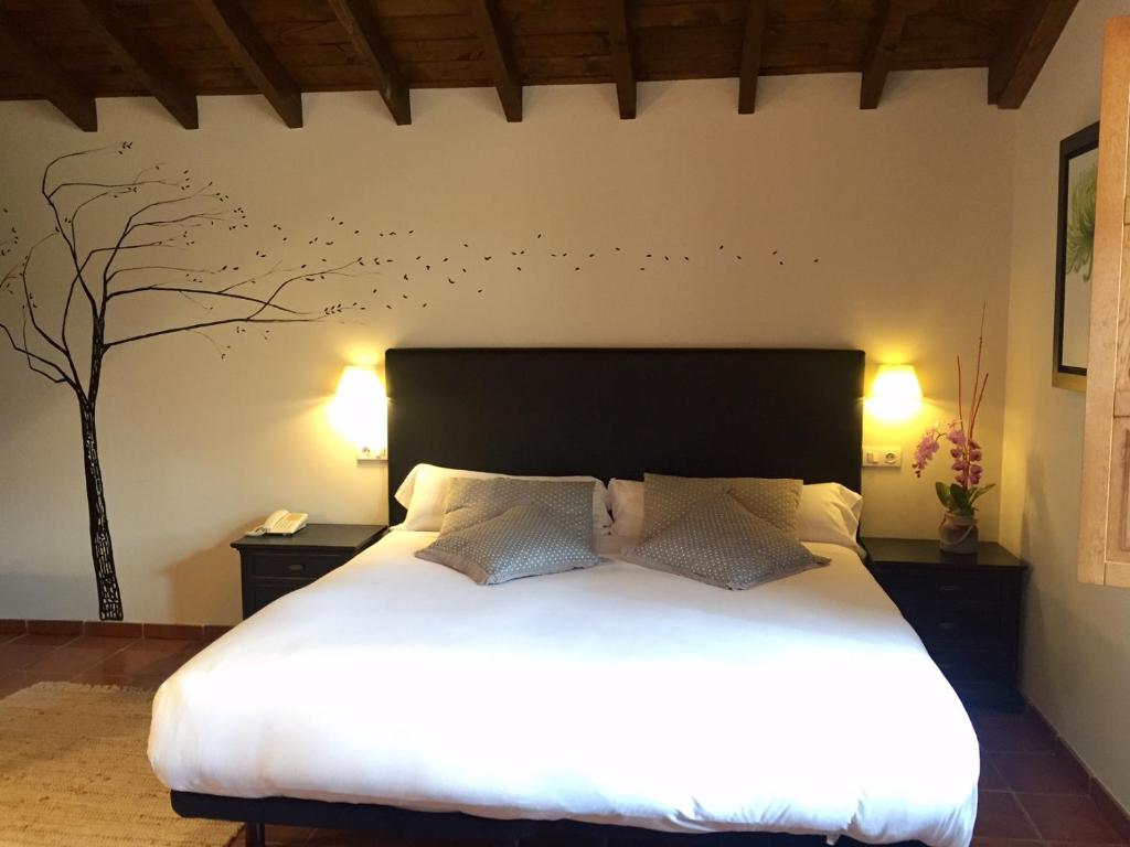 维多利亚-加斯特伊兹厄尔库托酒店及餐厅的卧室配有一张床,墙上有一棵树