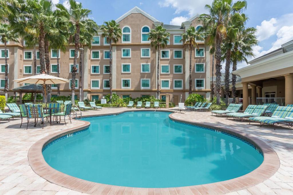 奥兰多Hawthorn Extended Stay by Wyndham Orlando的一个带椅子的游泳池和一个位于酒店后面的酒店