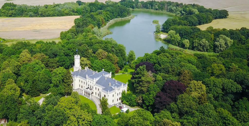 赖歇诺Romantik Hotel Schloss Reichenow的享有城堡和湖泊的空中景致