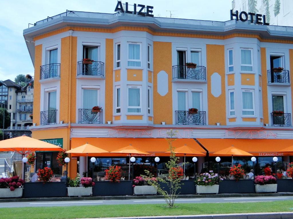 埃维昂莱班The Originals Boutique, Hôtel Alizé, Évian-les-Bains (Inter-Hotel)的一座建筑,里面是一座带橙色伞的alda酒店