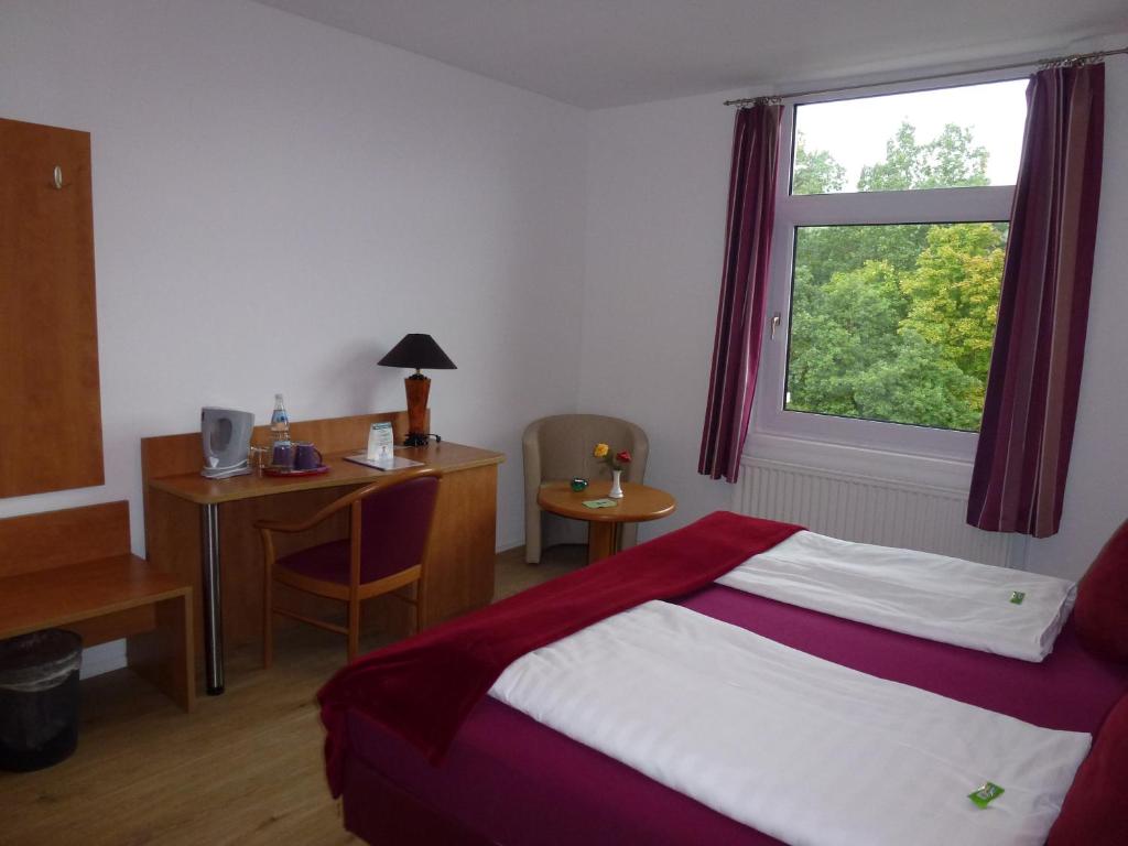 巴特维尔东根Hotel Wildunger Hof mit Gemeinschaftsküche的一间卧室配有一张床、一张书桌和一个窗户。