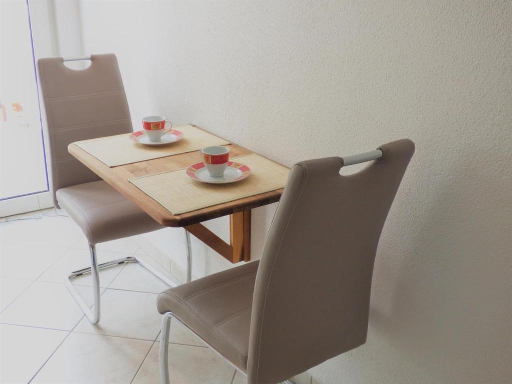 巴什卡沃达卢扎一室公寓酒店的一张木桌,带两个杯子和椅子