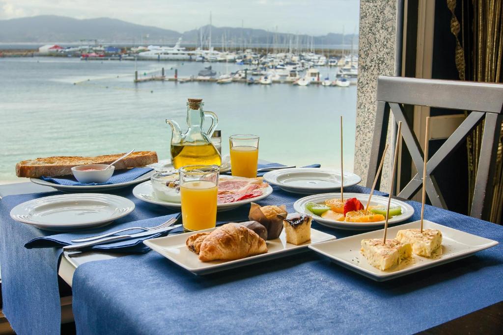 桑亨霍奥桑多马尔酒店的一张桌子上放着食物和饮料,享有海港景色