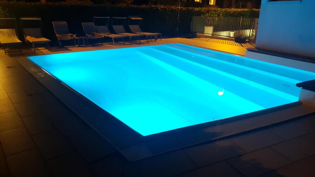西尔米奥奈Sirmione Rosselli Apartments的夜间游泳池,灯光蓝色