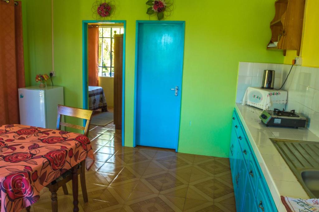 Rodrigues IslandMerlin Guest House的厨房设有蓝色的门、桌子和冰箱。