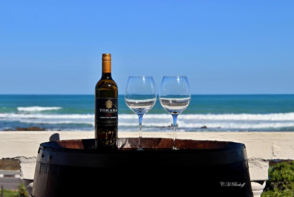 干斯拜Walkerbay Accommodation的海滩上桶装一瓶葡萄酒和两杯酒杯