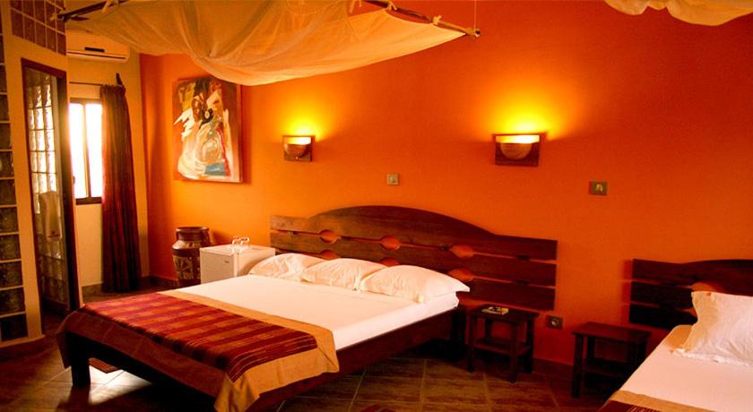 图利亚拉Hôtel Serena的一间卧室设有一张大床和橙色的墙壁