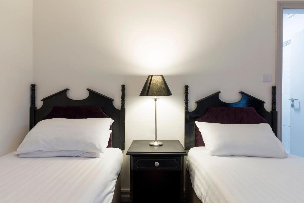 卡斯尔巴Ivy Tower Hotel的一间卧室配有两张床和床头灯。