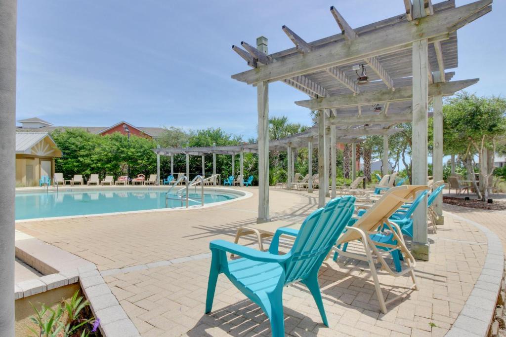 德斯坦The Beach Resort的一个带蓝色椅子的游泳池以及木制凉亭