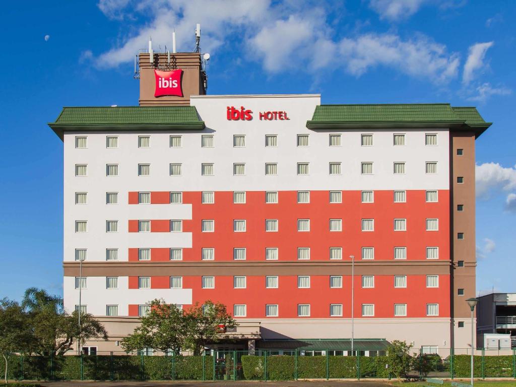 阿雷格里港阿雷格里港机场宜必思酒店的一座红色和白色的大建筑,上面有公共汽车标志
