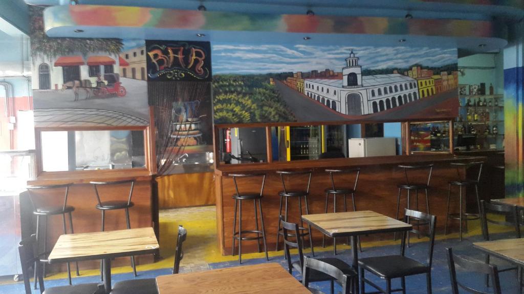 圣何塞Hotel Latino的墙上挂着带凳子和壁画的酒吧