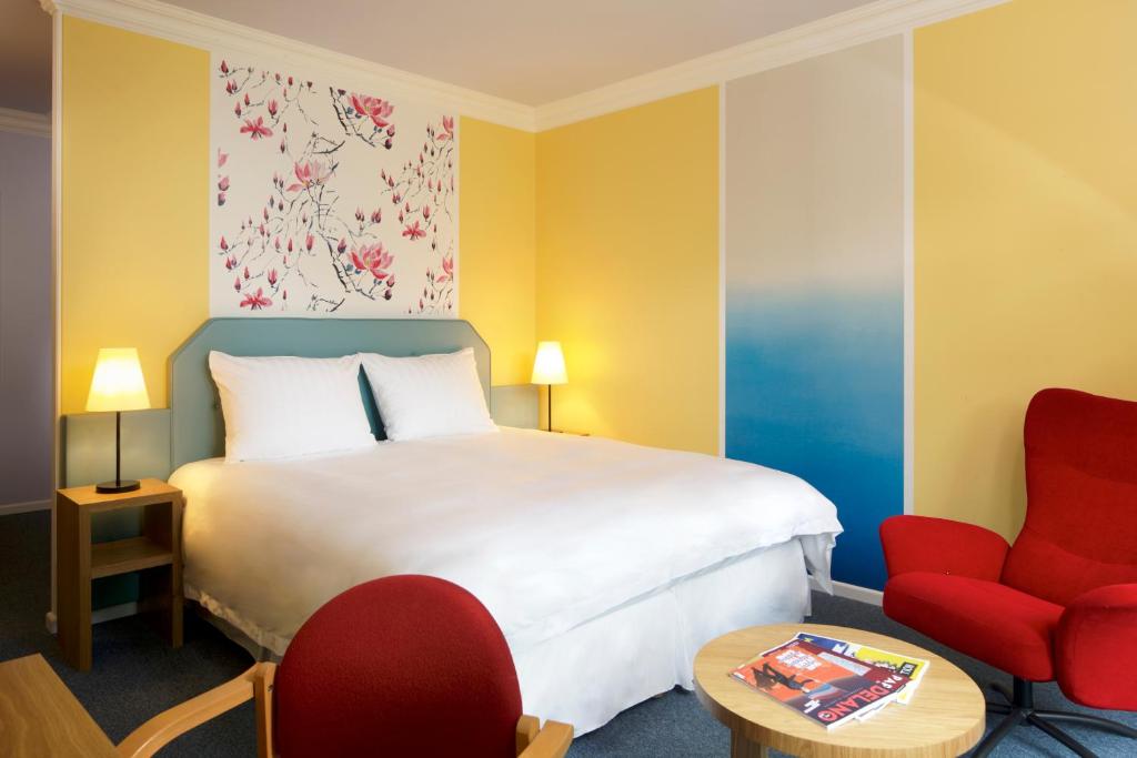 卢森堡卢森堡高瑞斯集团的酒店客房,配有一张床和一张红色椅子