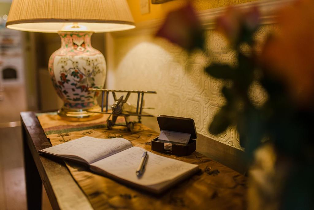 锡德茅斯Cheriton Guesthouse的一张桌子,上面有台灯,笔记本和笔