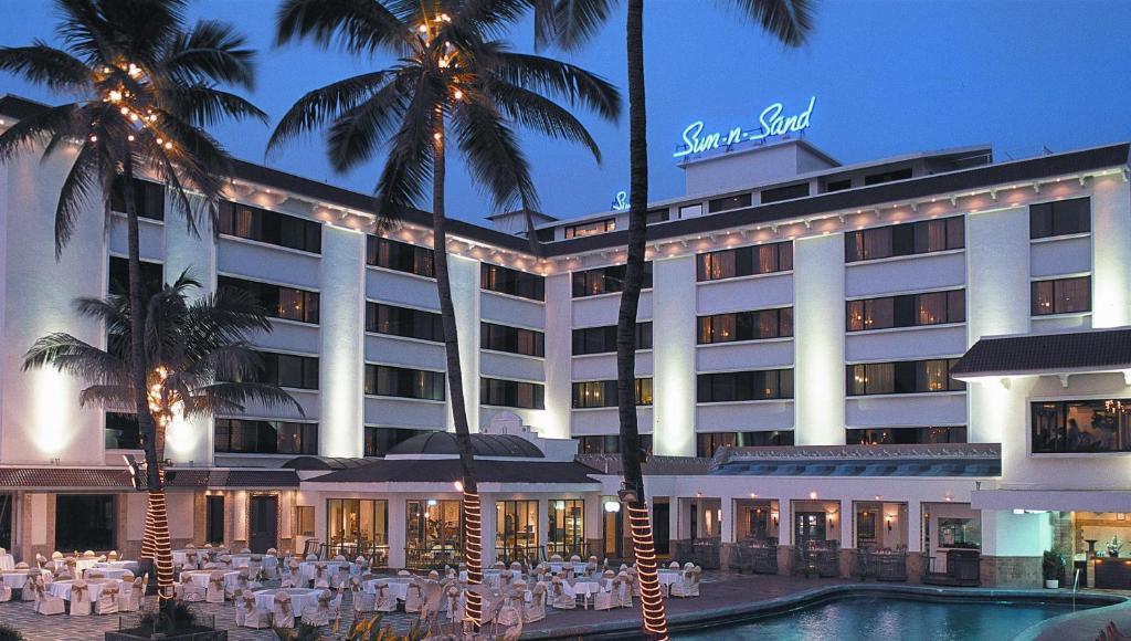 孟买Sun-n-Sand Mumbai Juhu Beach的一座酒店,前面有一个游泳池和棕榈树