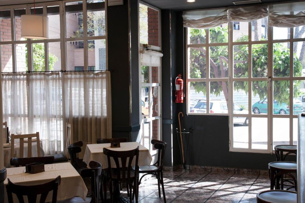 阿尔阿马德穆尔西亚洛斯巴尔托洛斯酒店的餐厅设有桌椅和大窗户。