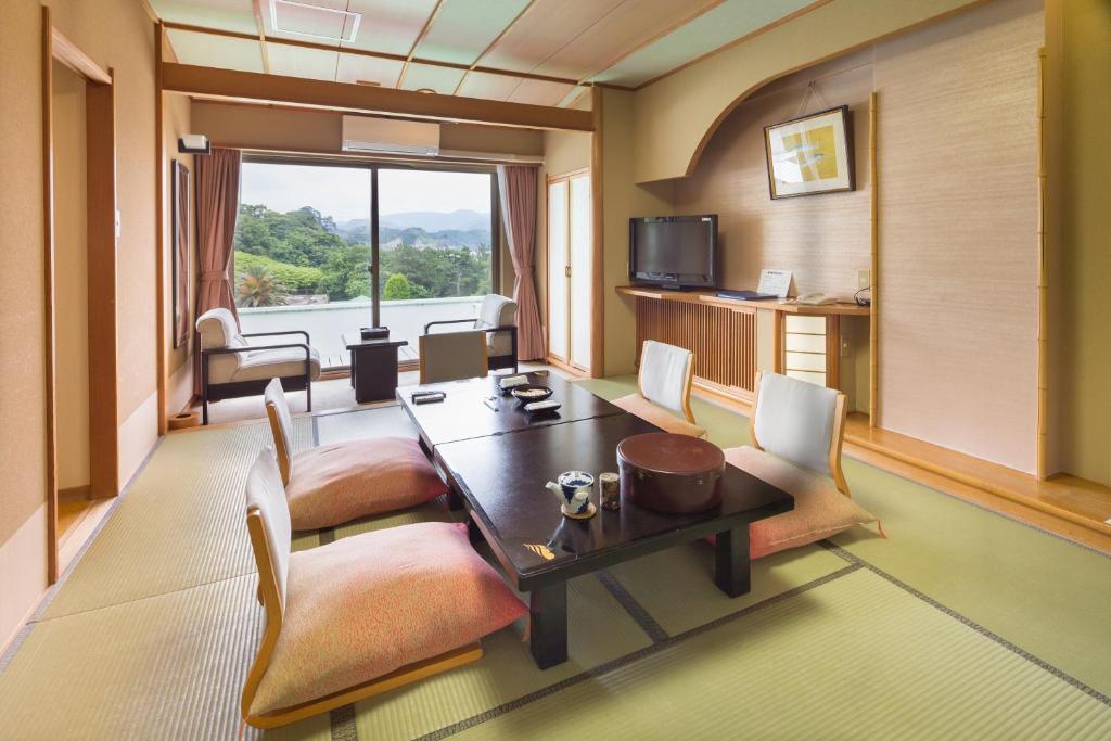 西伊豆町堂岛温泉日式旅馆的配有桌椅和电视的客房