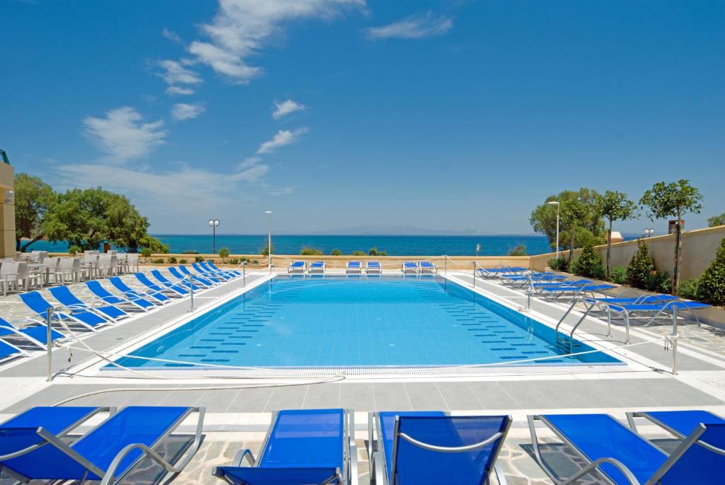 卡法斯爱琴海之梦酒店的一个带椅子的游泳池,背景是大海