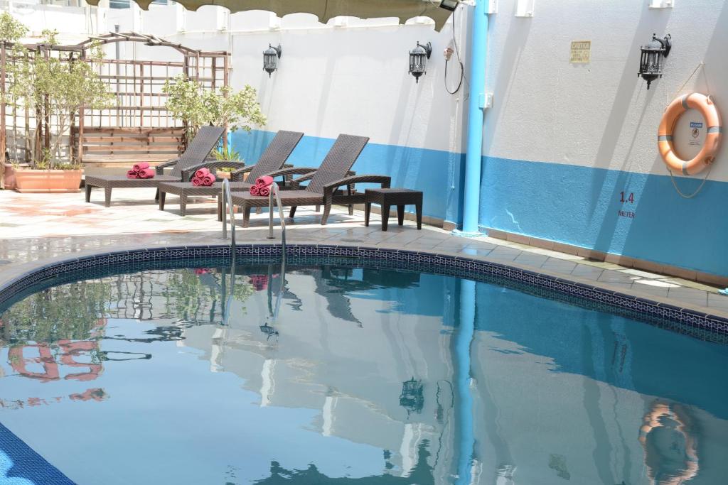 沙迦Spark Residence Hotel的一个带两把椅子和一张桌子的游泳池