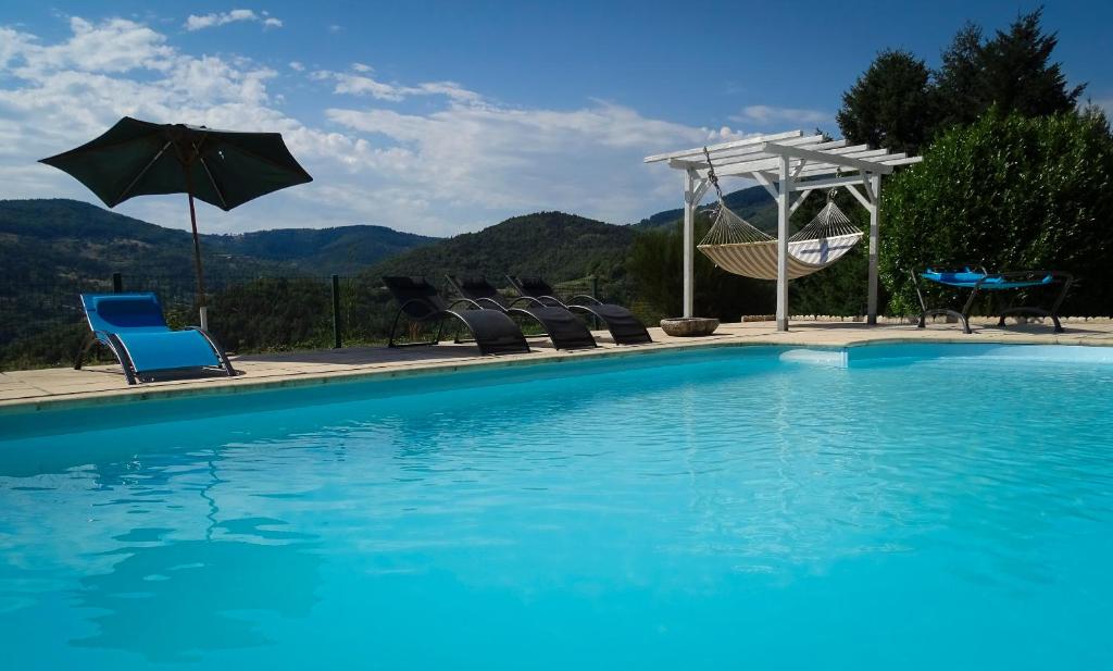 Empurany乐库洛扎特酒店的蓝色游泳池配有椅子和遮阳伞
