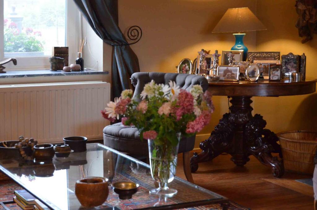 Mettet莱斯格兰斯住宿加早餐旅馆的客厅配有椅子和一张带花瓶的桌子