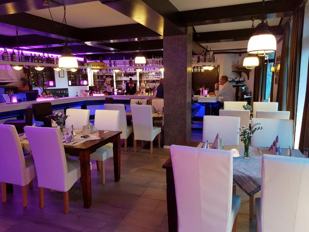 基尔霍诺酒店的一间带桌子和白色椅子的餐厅和一间酒吧