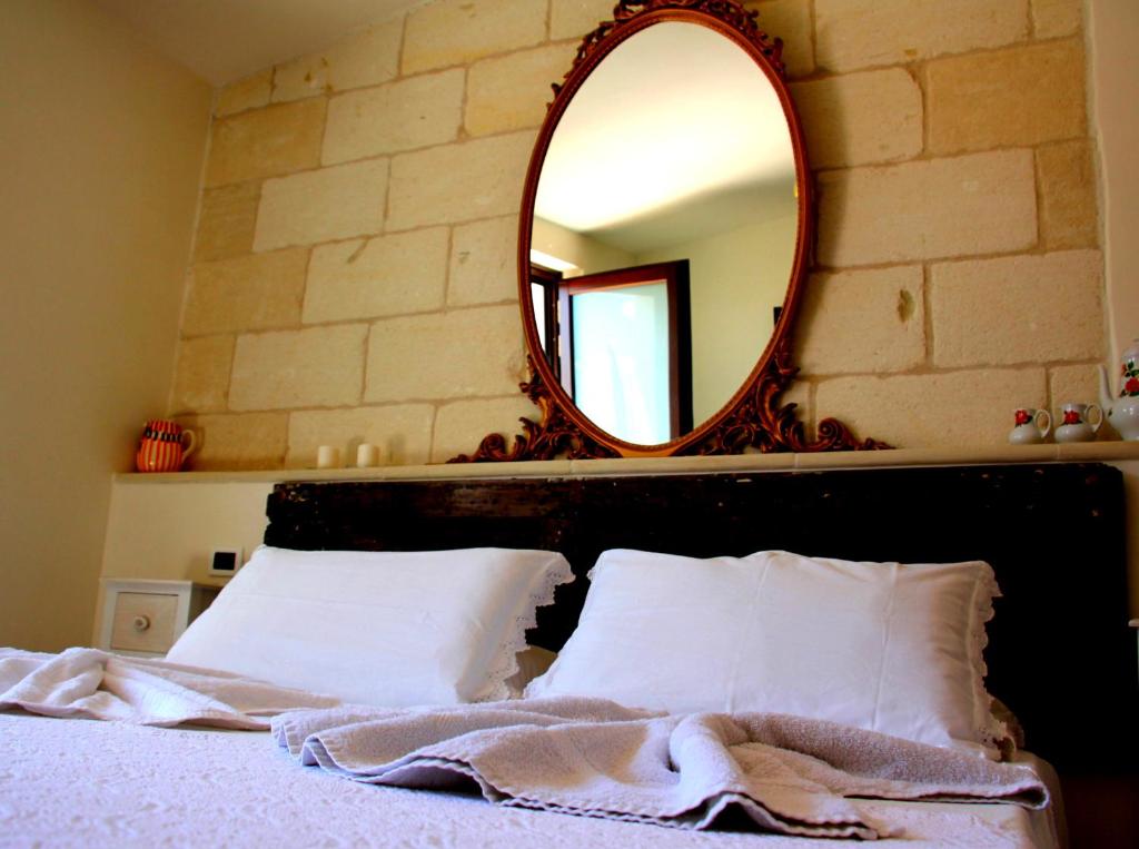 奥斯图尼Casa di Anna的一间卧室配有镜子和一张带白色枕头的床