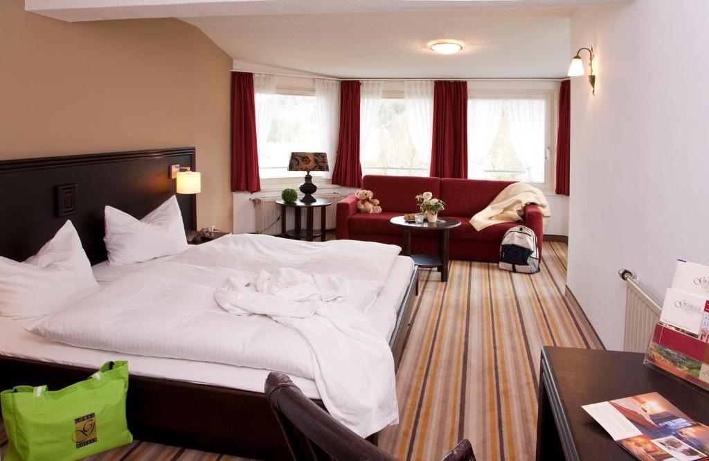 维林根Göbel's Gästehaus Hotel am Park的卧室配有一张白色的大床和一张沙发。