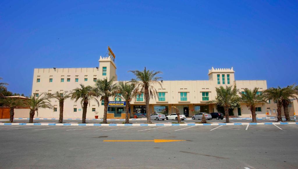 萨拉克Bahrain Beach Bay的停车场内棕榈树的大型建筑