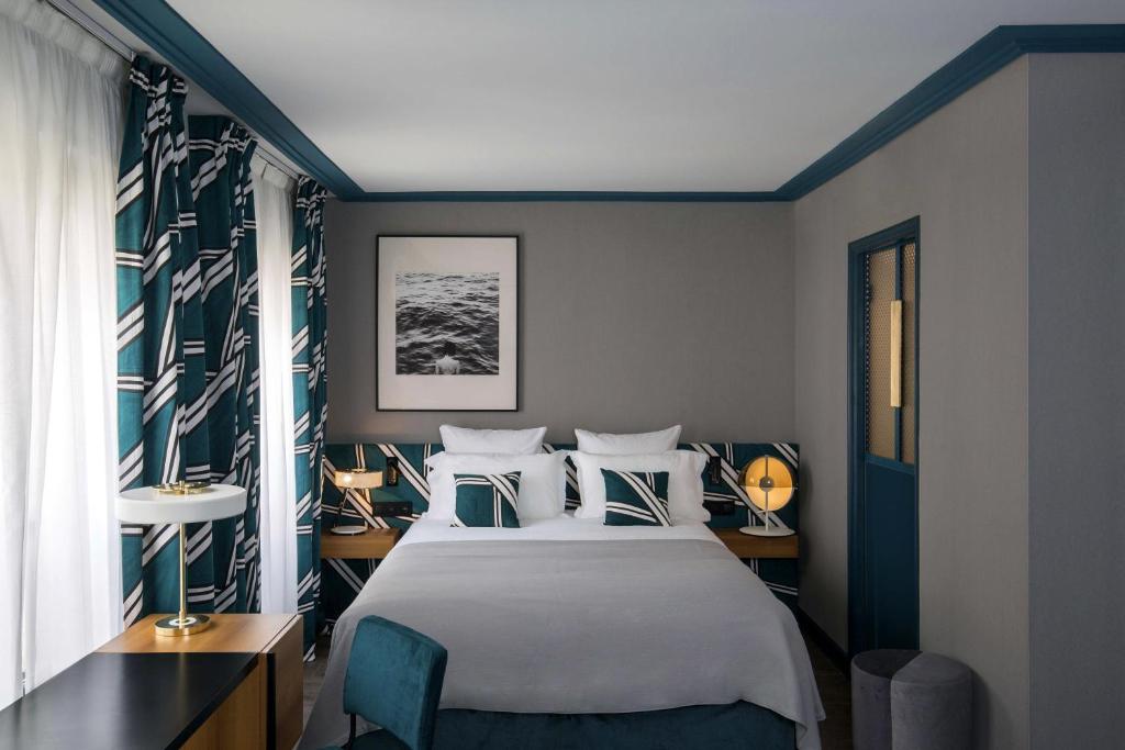巴黎皮埃蒙特卢浮宫酒店的卧室配有白色大床和蓝色的墙壁