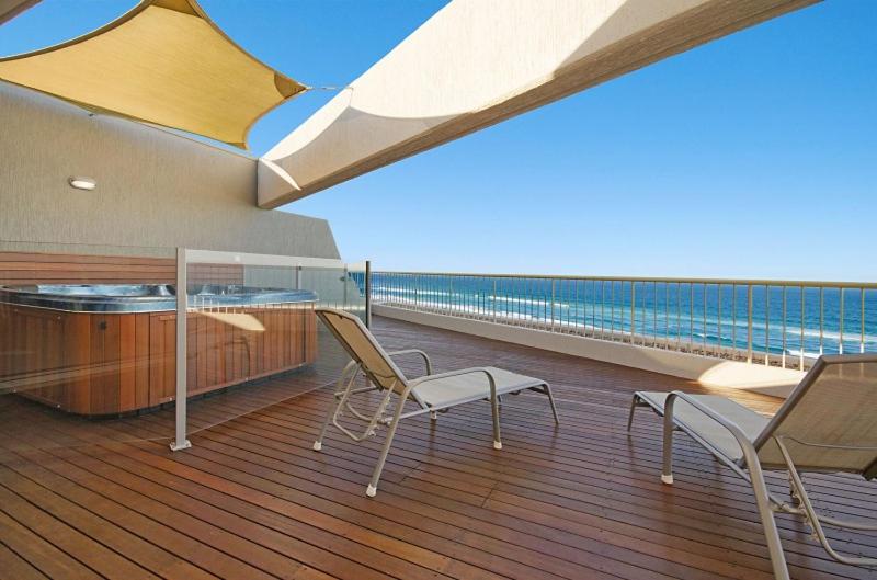 阳光海岸哥斯达新星假日公寓的船上的甲板上配有两把椅子和一张桌子