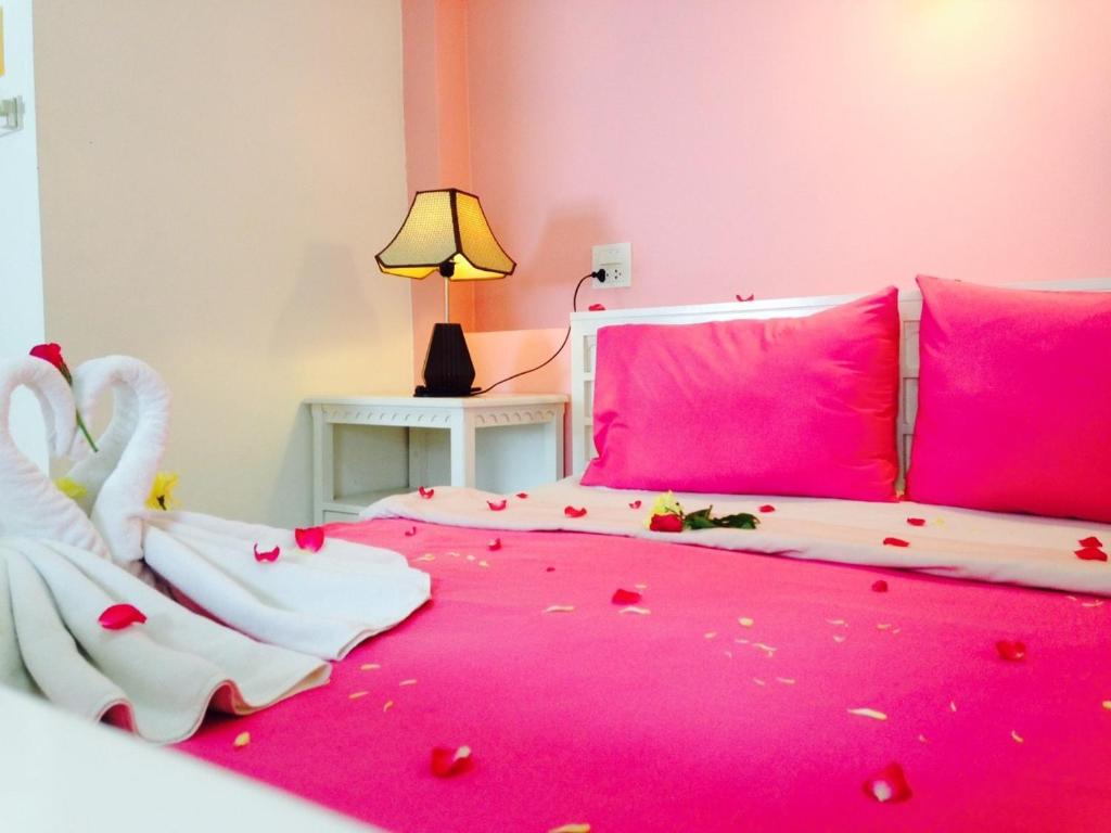 奥南海滩本之家酒店的粉红色的卧室,配有一张带盖的cuteti床铺