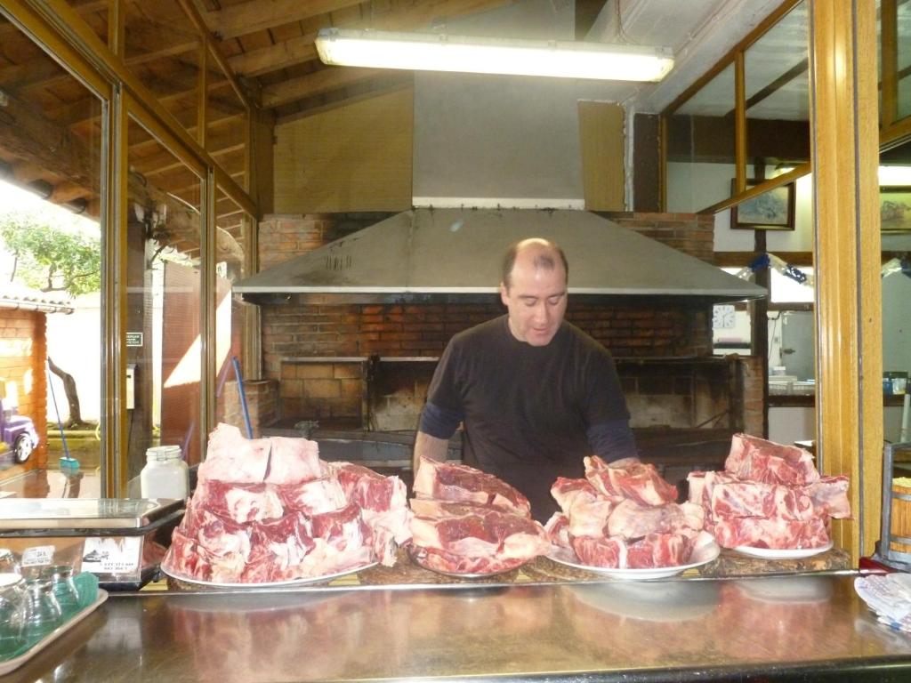 圣塞瓦斯蒂安Casa Rural Irigoien的站在柜台后面的人,有几架肉