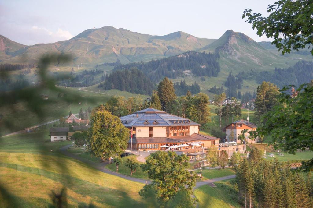 史多斯Wellness Hotel Stoos的一座大建筑,位于山丘上,背景是群山