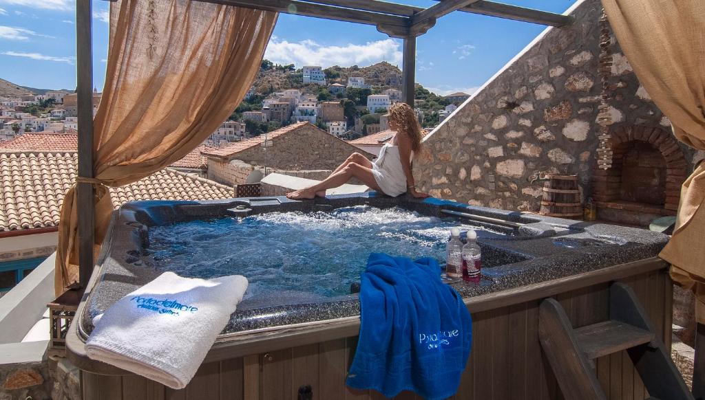 伊兹拉PortaDelMare deluxe suites的坐在阳台上热水浴缸中的女人