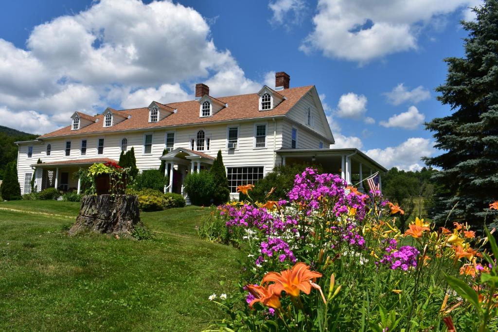 CheshireHarbour House Inn B&B的院子里的白色房子,鲜花盛开