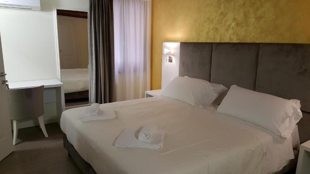 威尼斯精英之家旅馆的一间卧室配有一张大白色的床,上面有两个盘子