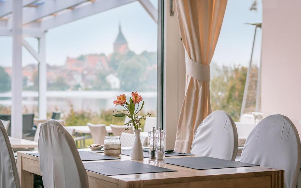 默尔恩Seehotel Schwanenhof的一张带白色椅子的木桌和大窗户