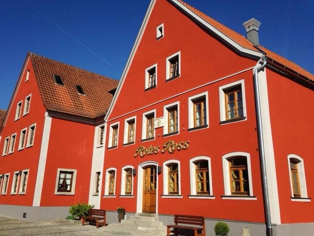 Markt Einersheim红马酒店的前面有长凳的红色大建筑