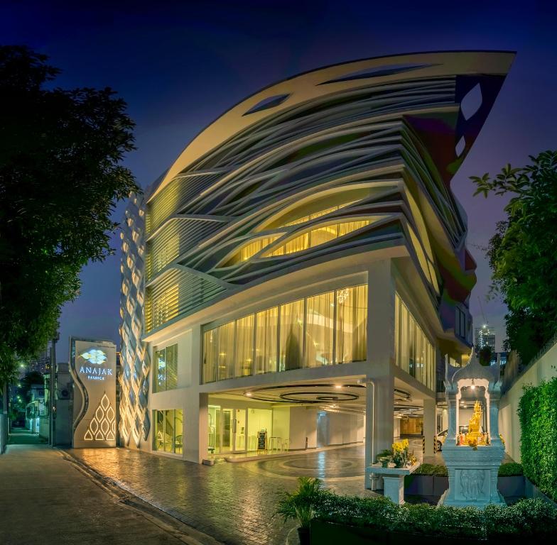 曼谷Anajak Bangkok Hotel - SHA Plus的一座在晚上有弧形外观的建筑