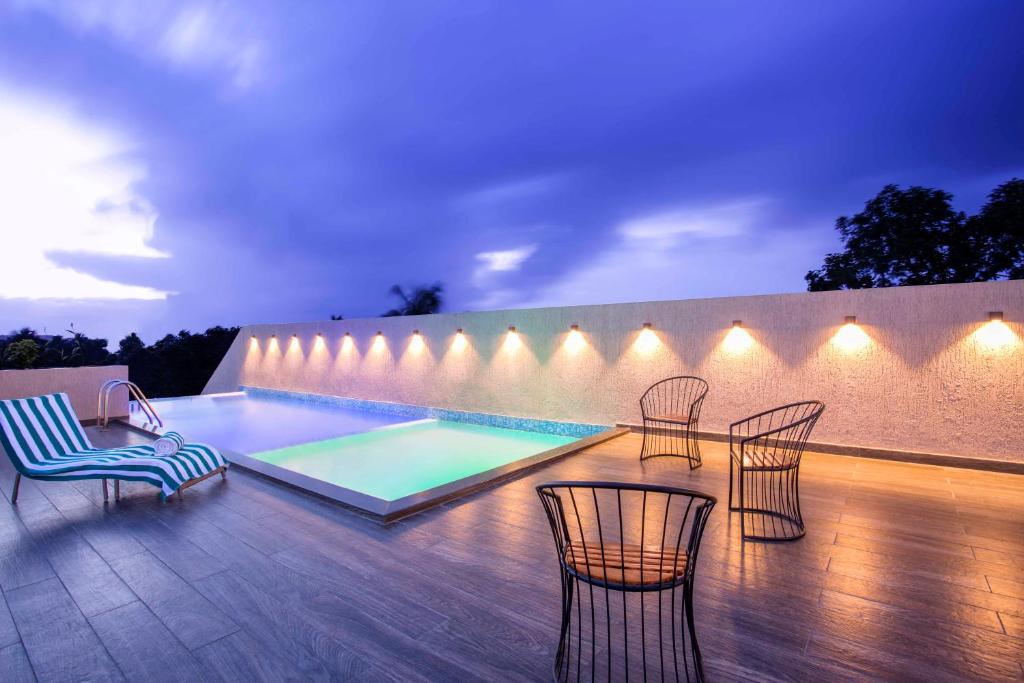 科钦Sidra Pristine Hotel and Portico Halls的一个带椅子的庭院和夜间游泳池