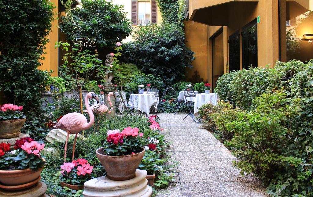 米兰米兰桑皮酒店的花园设有火烈鸟、桌子和鲜花