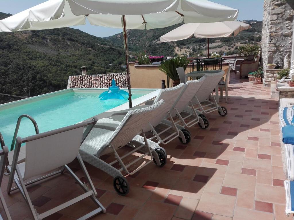 GuardialfieraB&B Il Belvedere的庭院内一个带椅子和遮阳伞的游泳池