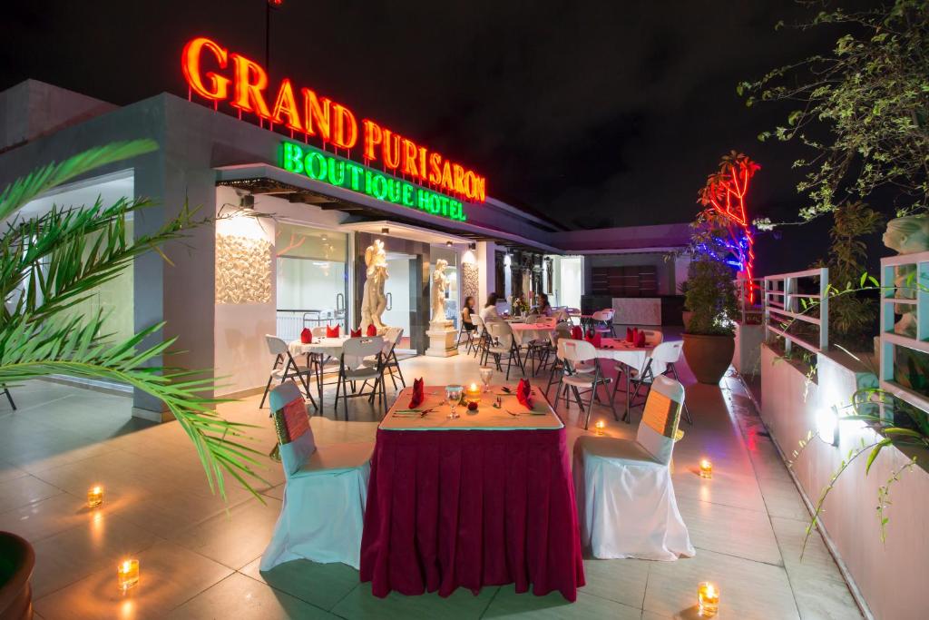 日惹日惹普里萨龙酒店的餐厅设有桌椅和 ⁇ 虹灯标志
