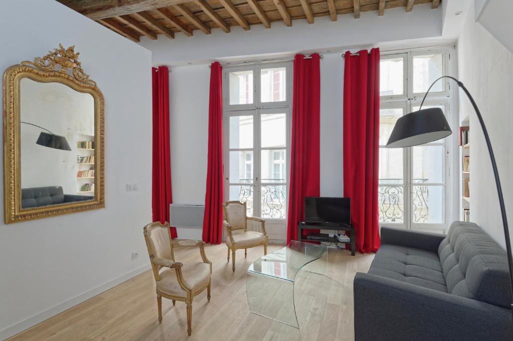 蒙彼利埃L'Argenterie, Apparts de charme climatisé parking gratuit的客厅配有红色窗帘、沙发和镜子