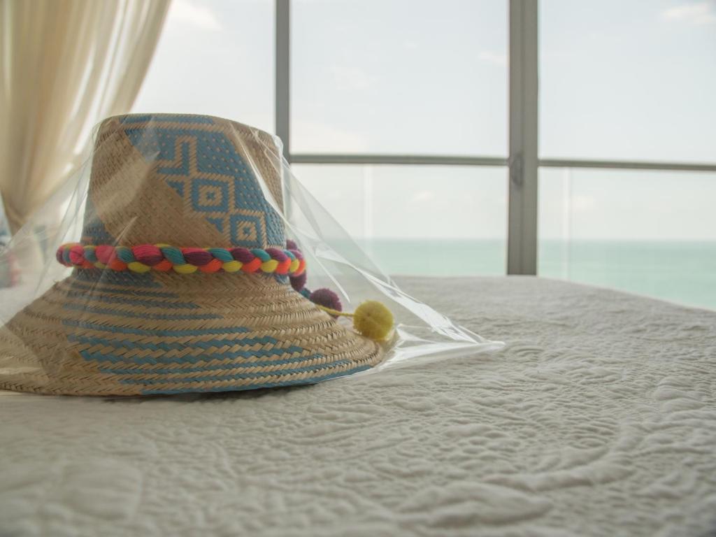 卡塔赫纳Luxury Alojamientos Namaste-Morros City的坐在床上的草帽