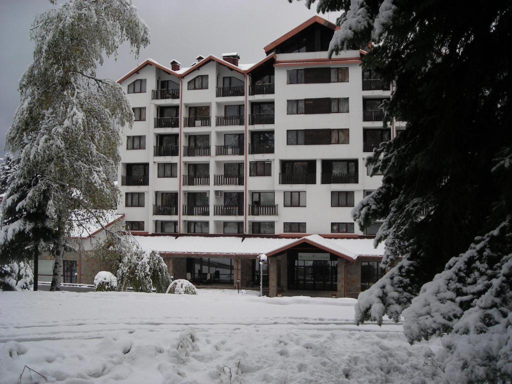 波罗维茨Borovets Gardens Chalet Flat的一座白色的大建筑,地面上积雪