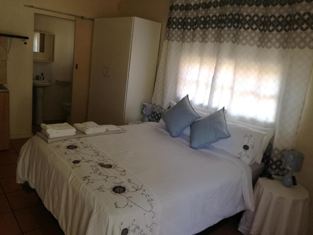 比勒陀利亚MulMas Guest House的卧室配有白色床、蓝色枕头和窗户